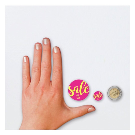 De afbeelding toont een hand met een lichte nagellak, aangevuld met twee ronde stickers met het woord 'sale' in felle kleuren en een munt van twee euro. De stickers zijn kleiner dan de hand en de munt.