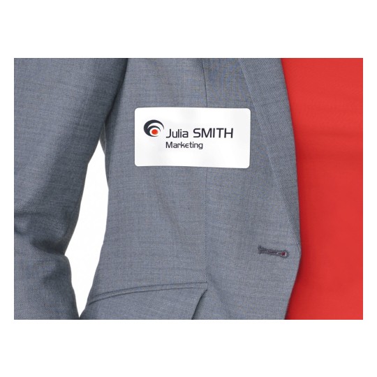 De afbeelding toont een close-up van een persoon in een grijze blazer met een naamlabel. Het label bevat de naam 'Julia SMITH' en het woord 'Marketing'.