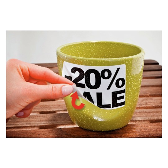 Afbeelding van een groene pot met een kortingslabel van 20% erop. Een hand verwijdert een sticker van de pot op een houten ondergrond.