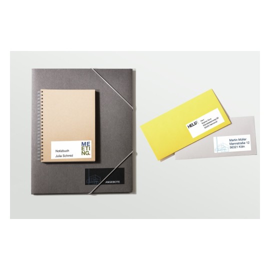 De afbeelding toont een notitieboek met de tekst 'Notizbuch Julia Schmid' en een paar enveloppen met adressen. Het notitieboek en de enveloppen hebben een professionele uitstraling.