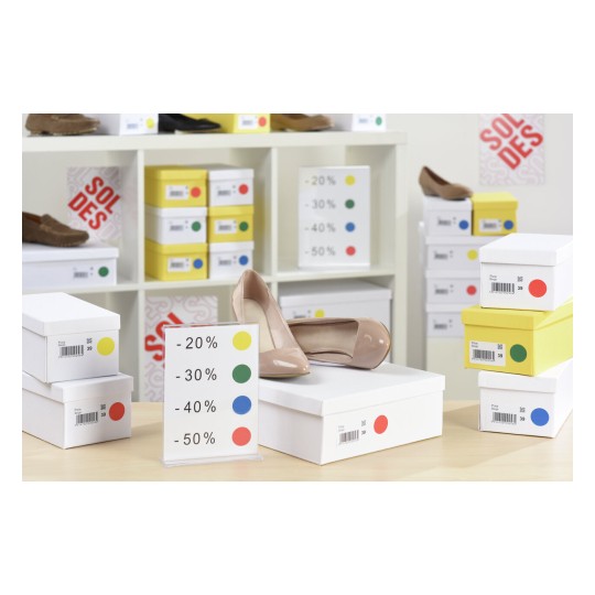 De afbeelding toont een display van schoenen met kortingen, gesorteerd in dozen en een bord met kortingspercentages.