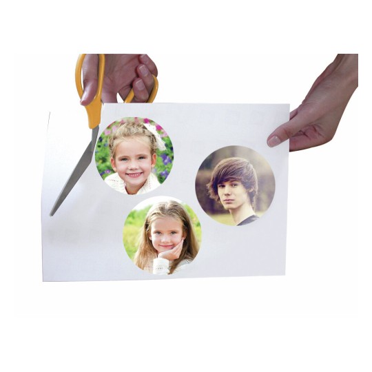Een hand houdt een papiertje met daarin drie gefotoshopte afbeeldingen van kinderen en een jongen terwijl het wordt geknipt.