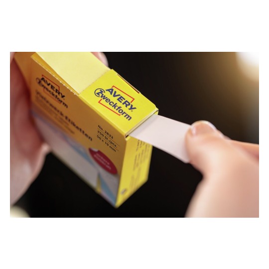 De afbeelding toont een hand die een papieretiket uit een doos trekt, met een gele doos van het merk Avery. De doos bevat 250 stuks etiketten van een specifieke afmeting.