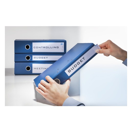 Een hand pakt een blauwe ringband met het label 'BUDGET' uit een stapel van drie ringbanden, getiteld 'CONTROLLING', 'BUDGET' en 'MEETING'.