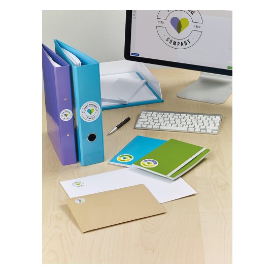 Het beeld toont een bureau met mappen en papier, waaronder gekleurde notitieboekjes en enveloppen, naast een computer.