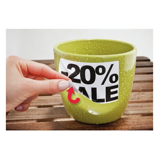 De afbeelding toont een groene bloempot met een kortingslabel waarop '-20% SALE' staat. Iemand trekt het label voorzichtig weg. De pot lijkt vochtig en er liggen houten planken onder.