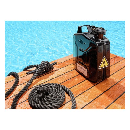 Het beeld toont een zwarte jerrycan met een waarschuwingslabel en een touw op een houten dek, met een zwembad op de achtergrond.