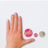 De afbeelding toont een hand met een lichte nagellak, aangevuld met twee ronde stickers met het woord 'sale' in felle kleuren en een munt van twee euro. De stickers zijn kleiner dan de hand en de munt.