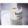 De afbeelding toont een rol met een label voor teakolie, gekleurd bruin. De rol heeft een glanzende afwerking en reflecteert op een oppervlak.