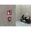 De afbeelding toont een muur met een brandveiligheidsbord en een rookafzuiging. Daarnaast staat een motorfiets geparkeerd in een speciale ruimte.