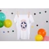 Een witte t-shirt met de tekst 'Niveau 5 Reussi!' en sterren eromheen, naast kleurrijke ballonnen.