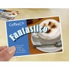 Deze afbeelding toont een koffiekaart van CoffeeCo met de tekst 'Fantastico', waaronder een foto van een cappuccino in een kopje. De achtergrond is beige en er is een lepel naast de kop.