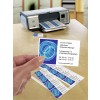 In de afbeelding is een printer zichtbaar die visitekaartjes afdrukt. Een hand houdt een visitekaartje vast met contactinformatie en een grafisch ontwerp. Het lijkt een kantoorsetting.