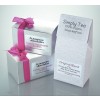 De afbeelding toont twee geschenkdozen met luxe handgemaakte truffels en een zak met losse thee. De truffels zijn verpakt in zilveren dozen met een roze strik, terwijl de theeverpakking een lichte, patroonrijke achtergrond heeft.