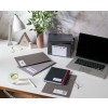 Op een bureau liggen verschillende kantoorbenodigdheden, waaronder een laptop, notitieboeken en hangmappen. Er is ook een plant en een glazen beker met limoen en citroen.