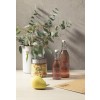 De afbeelding toont een moderne tafelsetting met een vaas eucalyptus, twee flessen met johannisbeeren, een doos met noedels en een peer.
