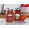 De afbeelding toont twee glazen potten met pastasaus. De linker pot heeft het etiket 'Tomate Noodlesaus' en de rechter pot heeft het etiket 'Tomate & Basilikum Noodlesaus'. Op de achtergrond zijn enkele tomaten te zien.