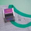 Dit beeld toont een kledingstempel met de tekst 'Clothing Stamp' bovenop een grijs shirt met groene hals.